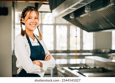 Portrait of a confident female chef in uniform at a modern kitchen restaurant. Professional expertise successful in her occupation presenting delicious food. - Powered by Shutterstock