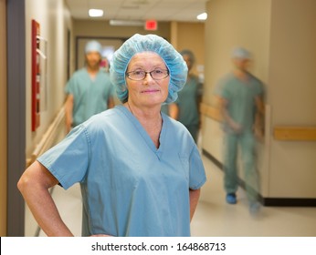 Portrait Of Confident Female Doctor With Team Walking In Hospital Corridor