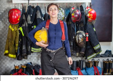 Portrait Of Confident Female Firefighter Holding Helmet While Standing At Fire Station