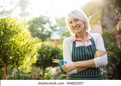 Portrait of confident female gardener standing by plants - Powered by Shutterstock