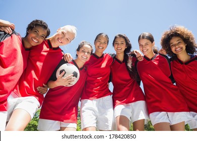 Portrait of confident female soccer team with ball against clear blue sky - Powered by Shutterstock