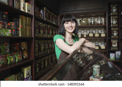 Portrait Of Confident Female Tea Shop Owner Leaning On Display Cabinet