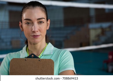 Portrait of confident female volleyball coach with clipboard at court - Powered by Shutterstock