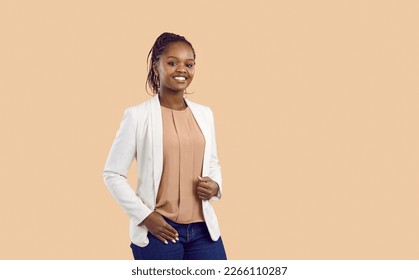 Portrait of confident, friendly and successful young dark skinned woman isolated on beige background. Millennial happy woman in jeans and jacket smiling looking at camera standing near copy space. - Powered by Shutterstock