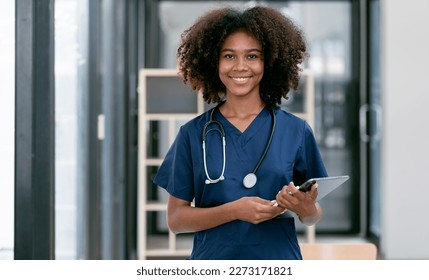 Portrait of confident, happy female nurse or doctor with stethoscope and tablet standing in hospital hallway, smiling to camera. - Powered by Shutterstock