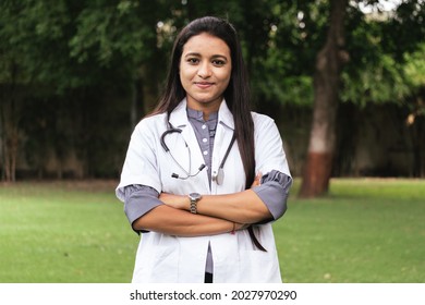 Portrait of confident Indian doctor wear white coat standing at outdoors with arms crossed on chest. Professional occupation person during covid-19, concept of medical service In India