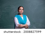 portrait of confident Indian teacher standing in front of the black board in class room