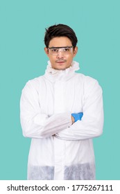 Portrait Of Confident Male Asian Researcher Scientist Medical Doctor Wearing Personal Protective Equipment (PPE), And Protection Glasses; Standing Cross Arms Isolated On Light Green Background