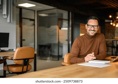 Portrait of confident male executive with hands clasped and in eyeglasses working at desk in office - Powered by Shutterstock