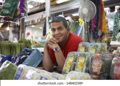 Portrait Of Confident Male Grocery Store Owner Smiling While Leaning On Counter