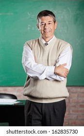 Portrait Of Confident Male Professor Standing Arms Crossed In Classroom