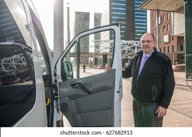 Portrait Of Confident Male Taxi Driver Standing By Van At Airport