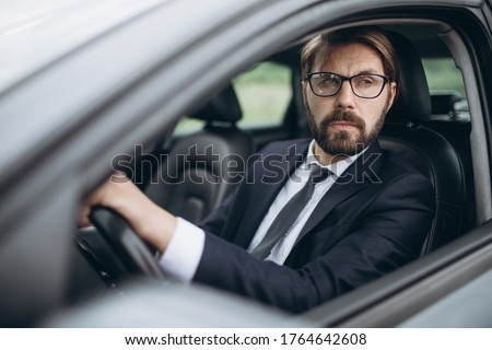 Portrait of confident man in eyewear and suit driving car