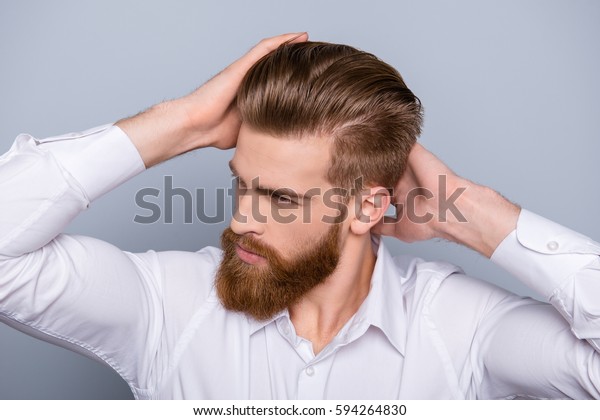Portrait of confident man with red beard touching
his hair