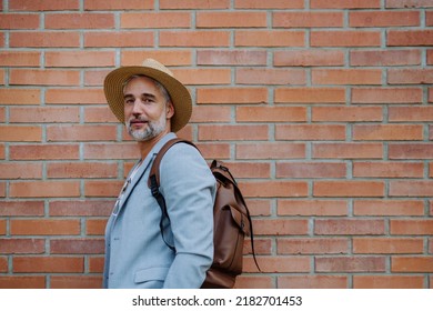 Portrait Of Confident Man Wearing Straw Hat And Backpack Looking At Camera, Businessman In Casual Clothes In Summer On The Way To Work.