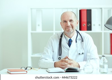 Portrait Of A Confident Mature Doctor Sitting At The Table And Looking At The Camera.