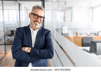 Portrait of confident mature gray-haired businessman standing with arms crossed, male office employee in formal wear, high-skilled expert looking at the camera and smiles, ready for new achivements - Powered by Shutterstock