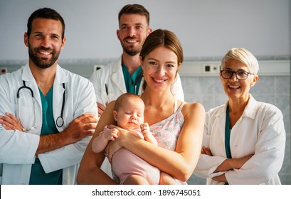 Portrait Of Confident Medical Team With Baby And Parent At Hospital