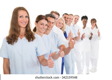 Portrait of confident medical team showing thumbs up while standing in line against white background - Powered by Shutterstock