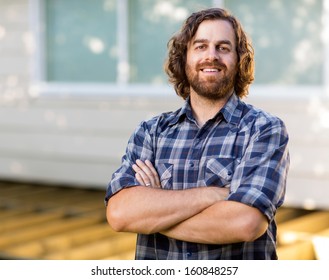 Portrait Of Confident Mid Adult Carpenter With Arms Crossed Standing At Construction Site