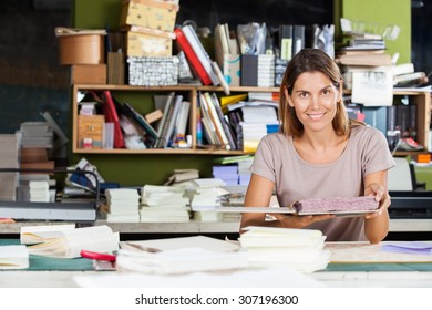 Portrait Of Confident Mid Adult Female Worker Holding Spiral Book In Factory