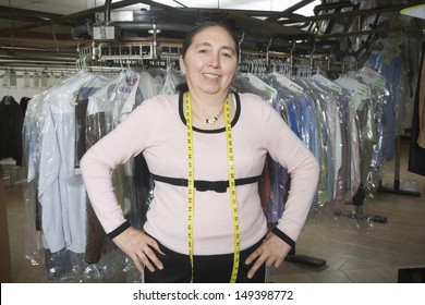 Portrait Of Confident Middle Aged Woman With Hands On Hips Standing In Laundry