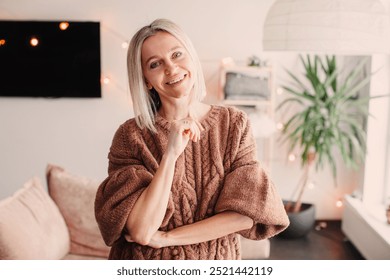 Portrait of confident Middle-aged Woman at home. Smiling 40s Lady dressed in Cozy knitted Sweater in her house
 - Powered by Shutterstock