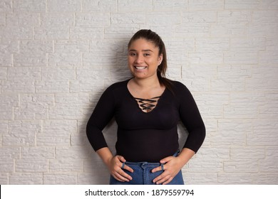 Portrait of  Confident overweight woman smilling at camera. Isolated on white brick wall