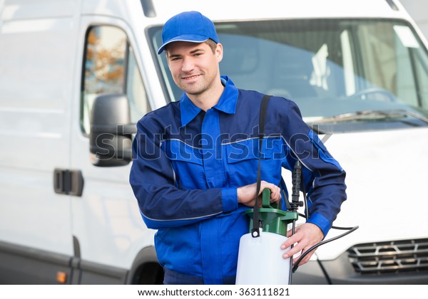 Portrait of confident pest control worker with\
pesticide against\
truck