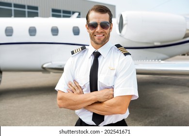 Portrait of confident pilot smiling in front of private jet