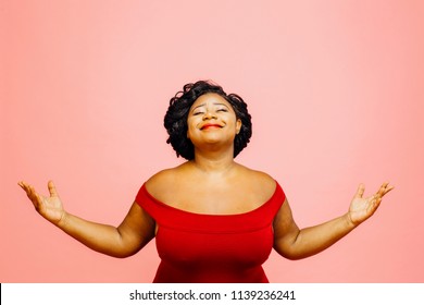 Portrait of a confident, satisfied and happy woman with both hands out, isolated on pink