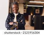 Portrait of confident senior black woman smiling and looking at camera with arms folded