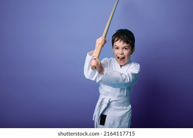 Portrait of a confident strong Caucasian child boy aikido wrestler wearing traditional samurai hakama kimono learning fight with bamboo bokken. Aikido Learning and Oriental martial arts Concept