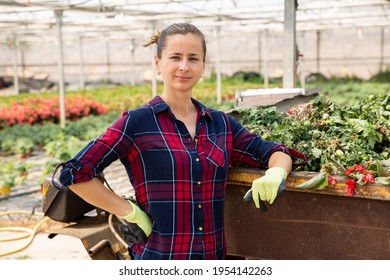 Portrait of confident successful female farmer standing near small farm tractor in her greenhouse - Powered by Shutterstock