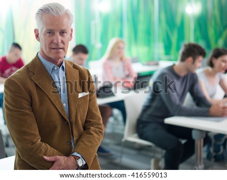 portrait of confident teacher in school classroom,  students group on class in background