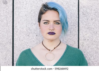 Portrait Of A Confident Teen Androgynous Woman With Blue Dyed Hair Isolated On The Street Wearing A Blue Sweater.