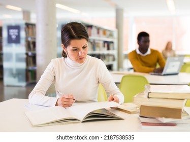 Portrait Of Confident Woman With Book In Public Library. High Quality Photo