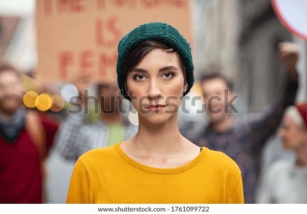 Portrait of confident woman in march\
fighting for freedom. Young latin woman empowerment strike on\
street. Casual girl in march to protest on equality\
rights.