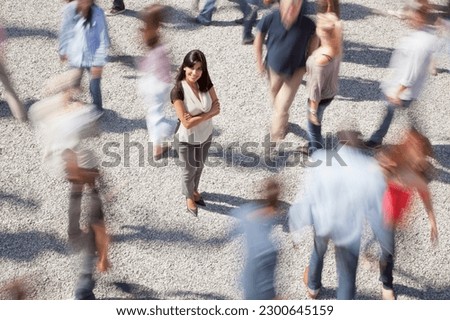 Portrait of confident woman standing among rushing crowd