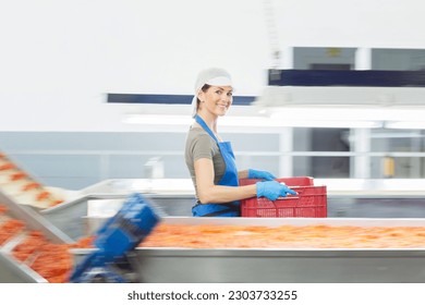 Portrait of confident worker carrying crate in food processing plant