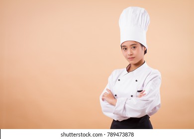 Portrait Of Confident Young Asian Woman Chef; Confident Woman Chef; Young Professional Female Cooking Staff, Girl Pastry Chef, Woman Cook Or Female Baker; Successful Asian Chef Studio Isolated