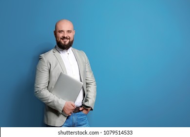 Portrait Of Confident Young Businessman With Laptop On Color Background