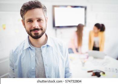 Portrait of confident young businessman standing in meeting room at creative office