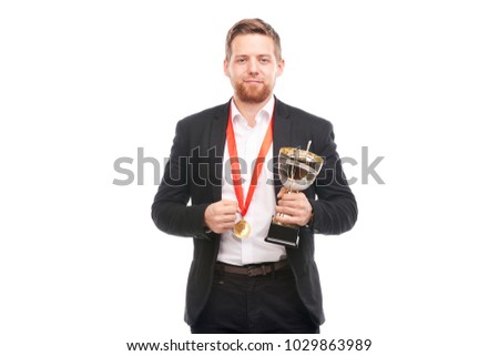 Portrait of confident young businessman wearing medal and holding trophy on white background