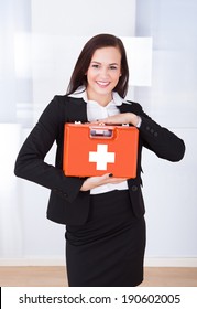 Portrait Of Confident Young Businesswoman Holding First Aid Box In Office