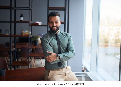 portrait of confident young handsome middle eastern businessman standing in office, looking at camera, successful team leader wearing formal wear, posing for photo at workplace - Shutterstock ID 1557149321