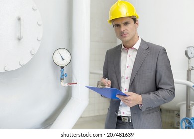 Portrait of confident young male inspector writing on clipboard in industry - Powered by Shutterstock