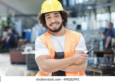 Portrait of confident young manual worker holding walkie-talkie in metal industry
