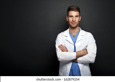 Portrait Of Confident Young Medical Doctor On Dark Background