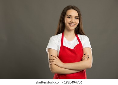 Portrait of a confident young supermarket employee wearing a red apron
